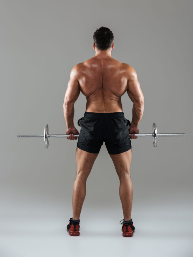 Back view full length of a muscular shirtless male bodybuilder